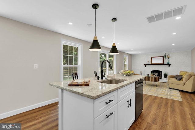 kitchen with hanging light fixtures, wood finished floors, visible vents, and a sink