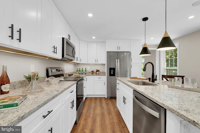 kitchen featuring light wood finished floors, recessed lighting, appliances with stainless steel finishes, and a sink