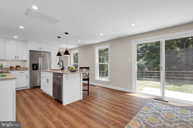 kitchen featuring visible vents, appliances with stainless steel finishes, wood finished floors, white cabinetry, and a sink