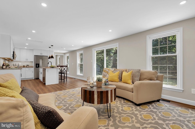 living room featuring recessed lighting, baseboards, and light wood-style flooring