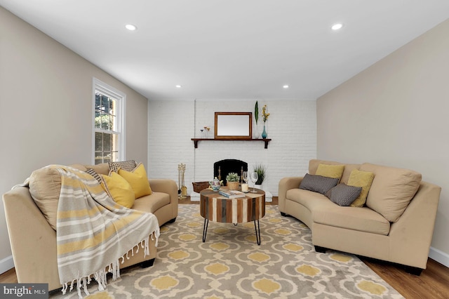 living area with recessed lighting, brick wall, a fireplace, and wood finished floors