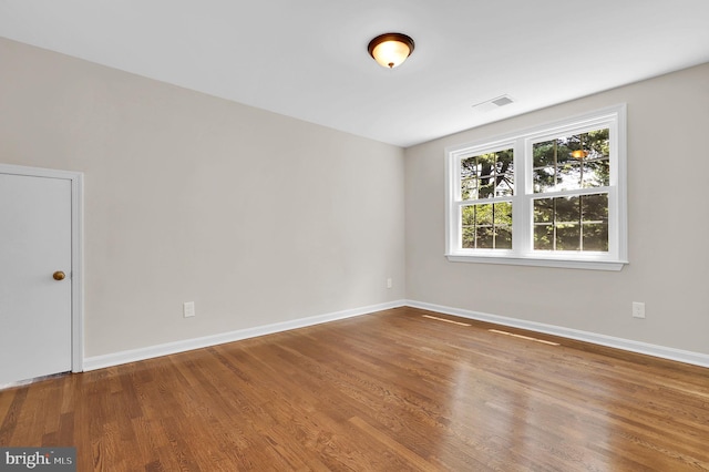 spare room featuring visible vents, baseboards, and wood finished floors