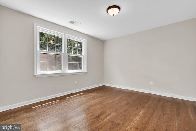 unfurnished room featuring visible vents, baseboards, and wood finished floors