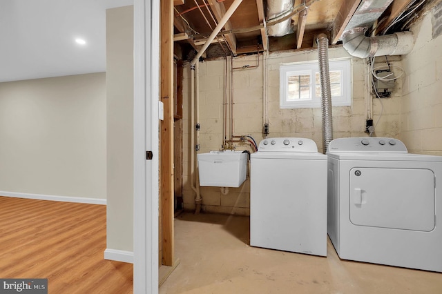 laundry area with a sink, wood finished floors, separate washer and dryer, baseboards, and laundry area