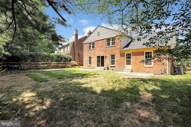 back of property featuring entry steps, fence, a yard, brick siding, and central AC unit