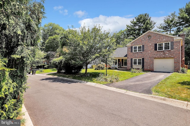 view of front facade with aphalt driveway, brick siding, a garage, and a front yard