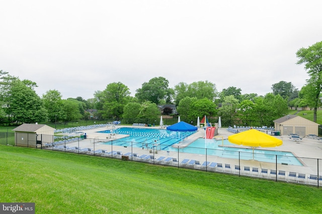 pool featuring a lawn, a water play area, and fence