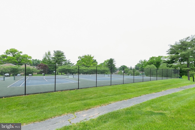 view of sport court with a lawn and fence