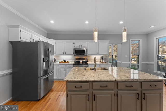 kitchen with a sink, appliances with stainless steel finishes, white cabinets, and light wood finished floors