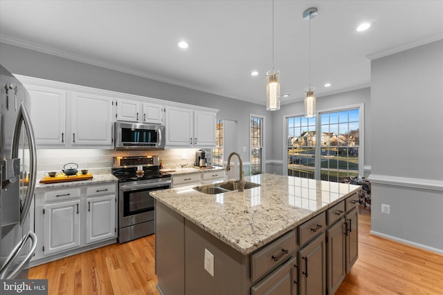 kitchen with a sink, appliances with stainless steel finishes, light wood-style flooring, and crown molding