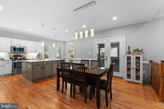 dining space featuring french doors, crown molding, and light wood-style floors