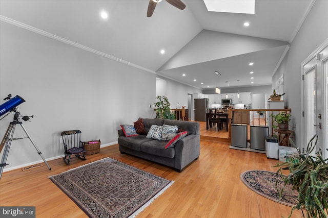 living room with light wood finished floors, visible vents, crown molding, baseboards, and vaulted ceiling with skylight