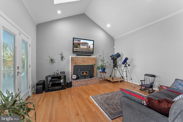 living area with a brick fireplace, a skylight, crown molding, and wood finished floors