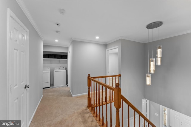 hallway featuring washer and dryer, an upstairs landing, light carpet, and crown molding