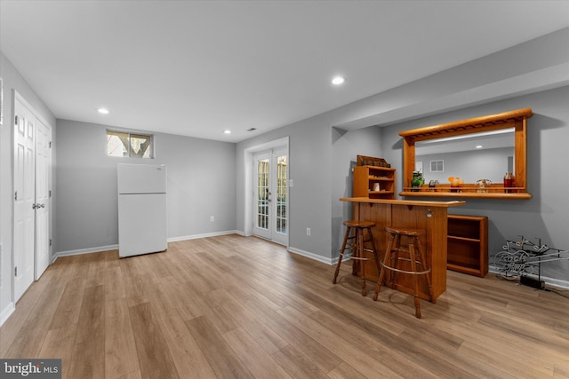 bar featuring a bar, recessed lighting, wood finished floors, and freestanding refrigerator