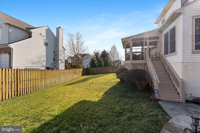 view of yard featuring stairs, a fenced backyard, and a sunroom