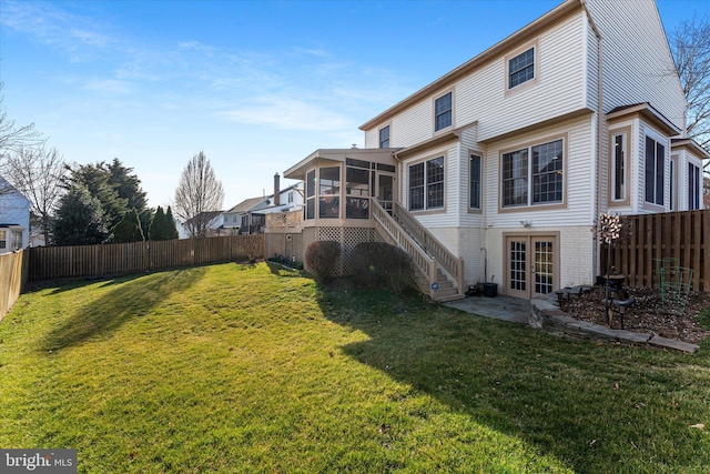 rear view of property featuring a lawn, french doors, a fenced backyard, and a sunroom