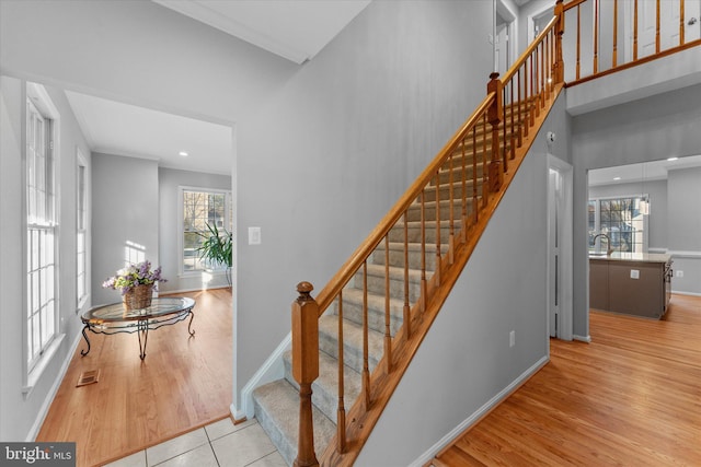 staircase with visible vents, plenty of natural light, baseboards, and wood finished floors