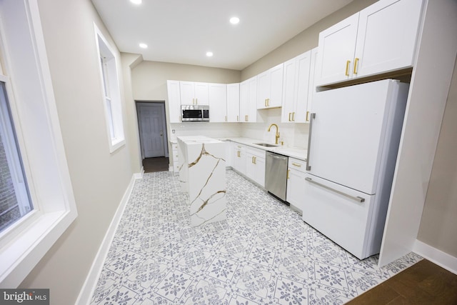 kitchen featuring a sink, stainless steel appliances, baseboards, and white cabinetry