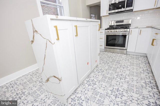 kitchen featuring tasteful backsplash, baseboards, light stone counters, white cabinets, and stainless steel appliances