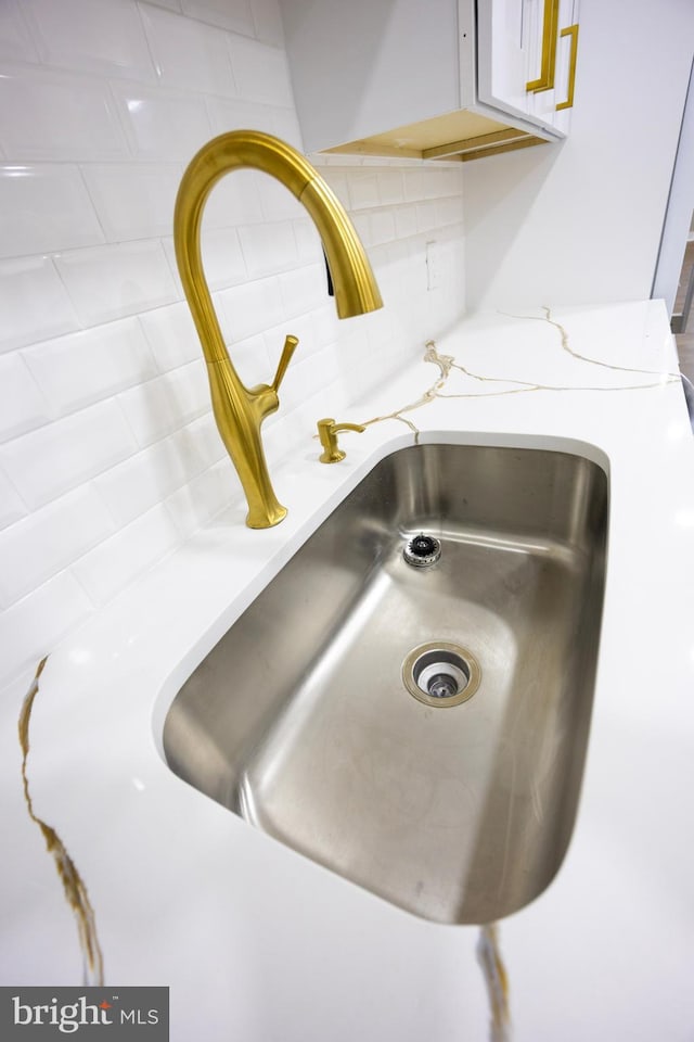 interior details with decorative backsplash, light stone countertops, and a sink