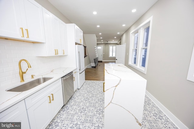 kitchen with freestanding refrigerator, a sink, decorative backsplash, white cabinets, and stainless steel dishwasher