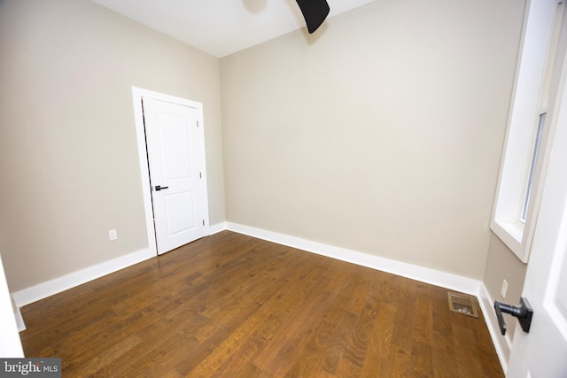 unfurnished room with dark wood-style floors, visible vents, ceiling fan, and baseboards