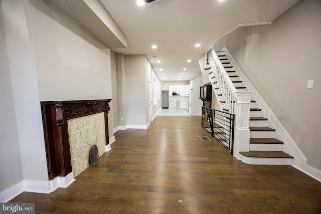 foyer entrance with baseboards, stairs, recessed lighting, a fireplace, and wood finished floors