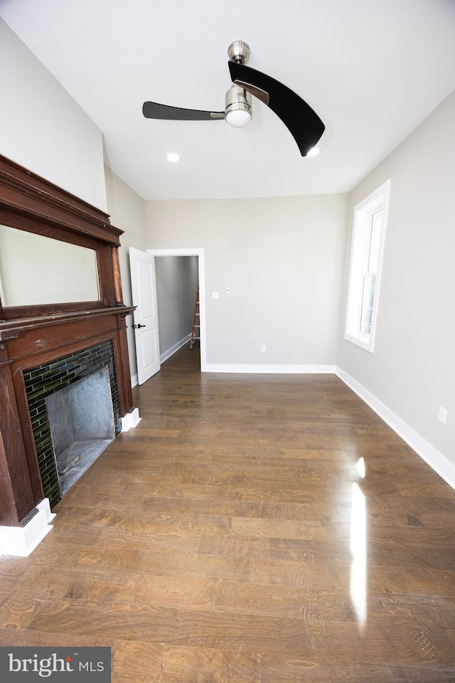 unfurnished living room featuring a fireplace, baseboards, ceiling fan, and wood finished floors