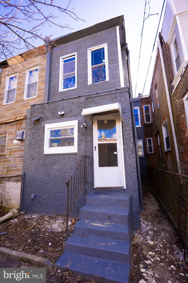 townhome / multi-family property featuring stucco siding, fence, and entry steps