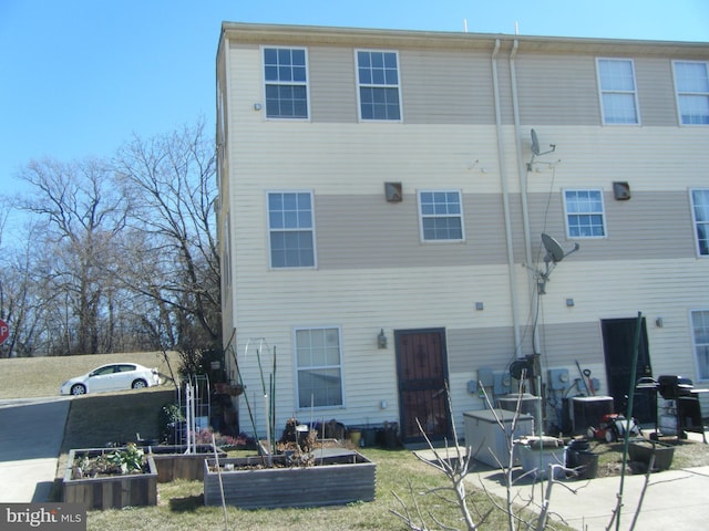 back of house with central air condition unit and a vegetable garden