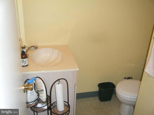 half bathroom with vanity, toilet, and baseboards