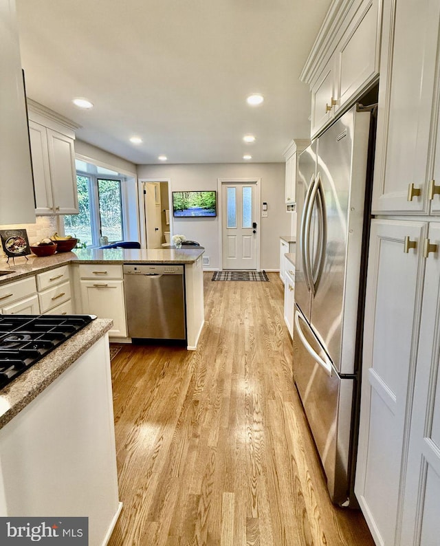 kitchen with white cabinets, light wood-style floors, and stainless steel appliances