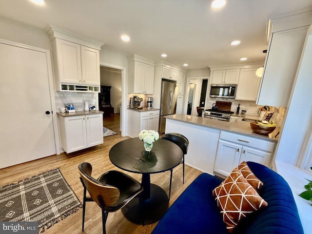 kitchen with light wood-style flooring, appliances with stainless steel finishes, white cabinets, and a sink