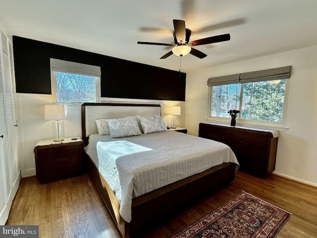 bedroom with multiple windows, baseboards, and wood finished floors