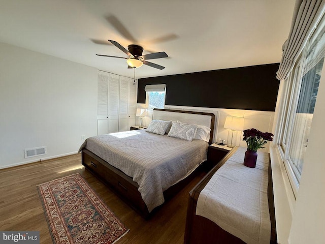 bedroom featuring visible vents, baseboards, wood finished floors, a closet, and a ceiling fan