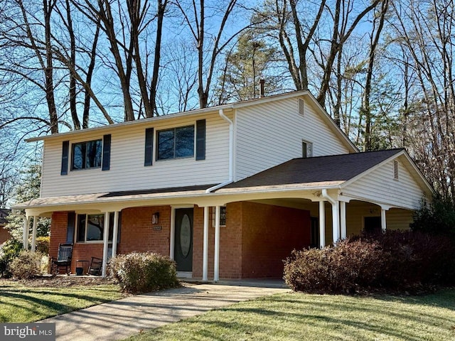 traditional-style home featuring a porch, concrete driveway, a front yard, a carport, and brick siding