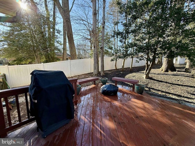 wooden terrace with grilling area and a fenced backyard