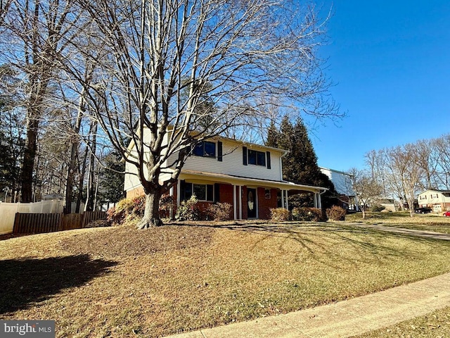 traditional-style house with brick siding, a front lawn, and fence