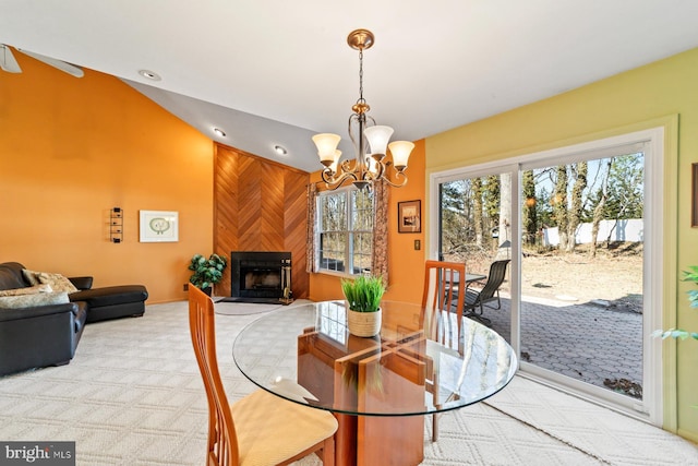 dining space with a wealth of natural light, a large fireplace, light carpet, and vaulted ceiling