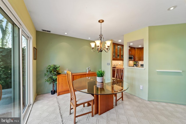 dining room featuring light carpet, visible vents, a chandelier, and baseboards