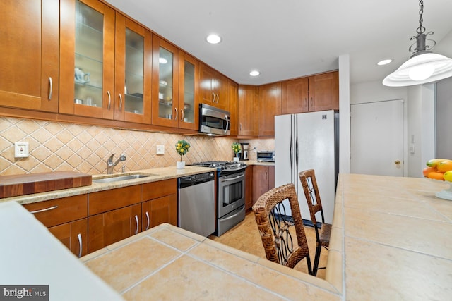 kitchen with a sink, brown cabinets, tasteful backsplash, and appliances with stainless steel finishes