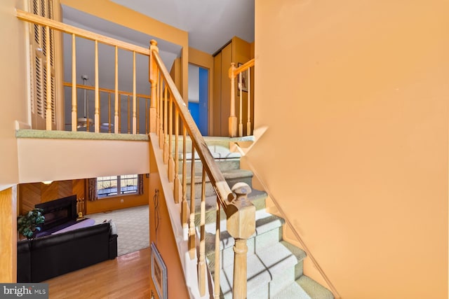 stairs featuring wood finished floors and a fireplace