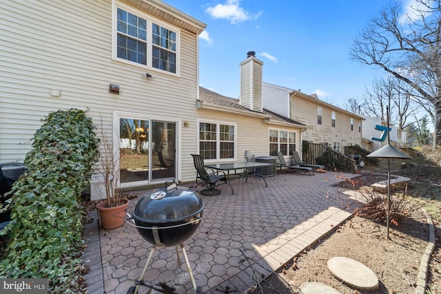 rear view of house featuring a chimney and a patio area