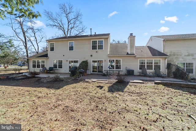 rear view of property featuring a patio, central AC, and a chimney