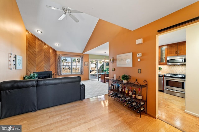 living area featuring lofted ceiling, ceiling fan with notable chandelier, and light wood finished floors