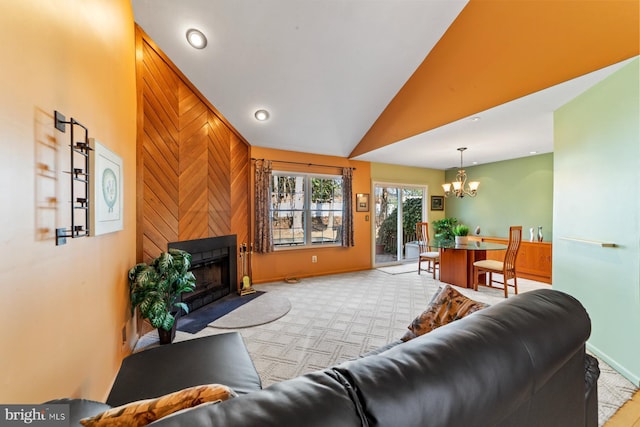 living room featuring baseboards, light colored carpet, lofted ceiling, a fireplace, and a notable chandelier