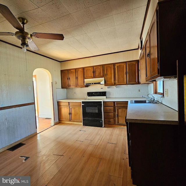 kitchen featuring visible vents, range with electric cooktop, under cabinet range hood, a sink, and arched walkways