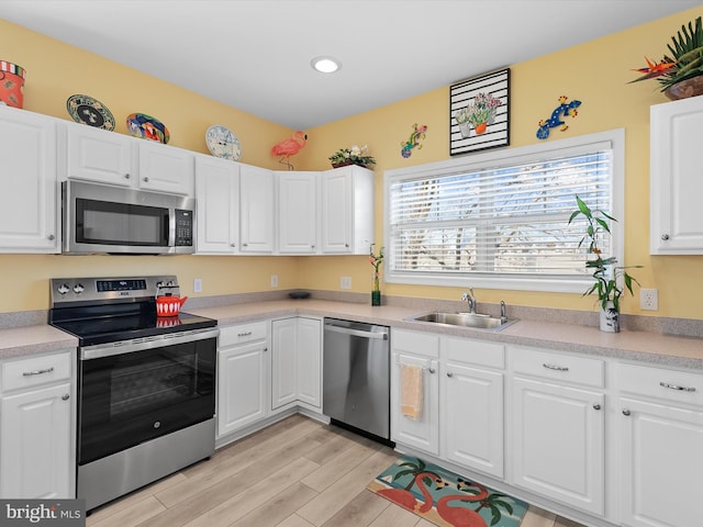 kitchen featuring a healthy amount of sunlight, light wood-type flooring, appliances with stainless steel finishes, and a sink