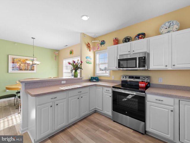 kitchen with wood tiled floor, a peninsula, stainless steel appliances, light countertops, and white cabinetry